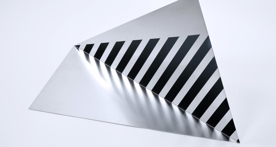 Metal piece in triangular shape that reflects a geometric pattern