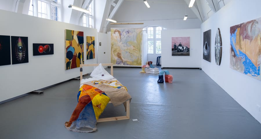 An exhibition space with painting on the walls and installations in the centre