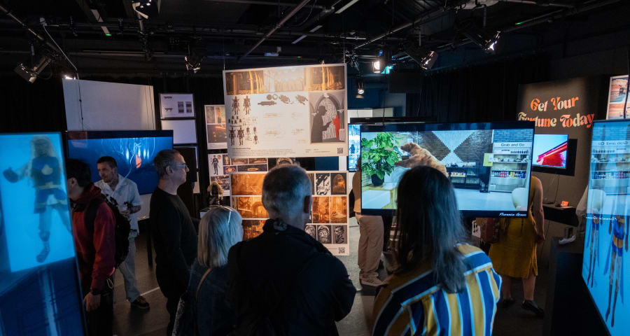 People looking at student work in a dark exhibition room