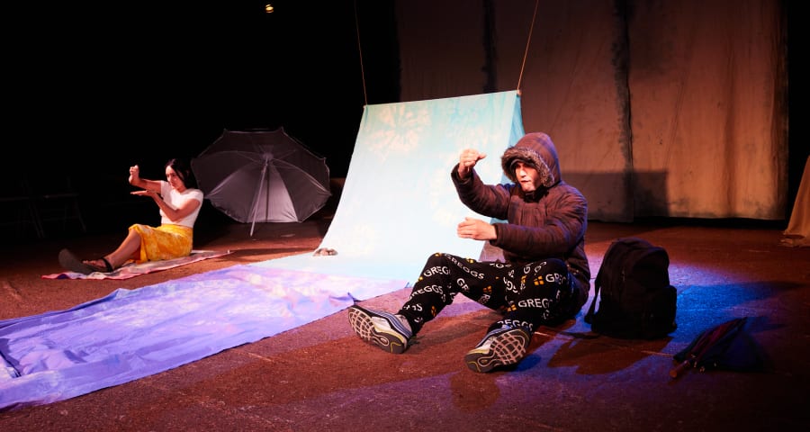 Man and woman in casual clothing onstage next to blue fabric