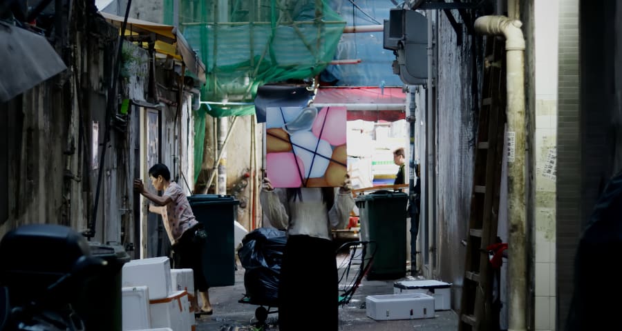 Artist holding their painting in an alleyway.