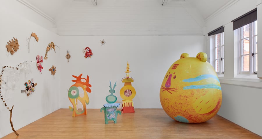 Large yellow inflatable bunny in a room with other green and yellow inflatable objects