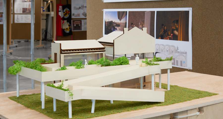 White sculpture of a house with a ramp and trees